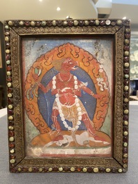 A Tibetan thangka in inlaid gilt brass frame, 19th C.